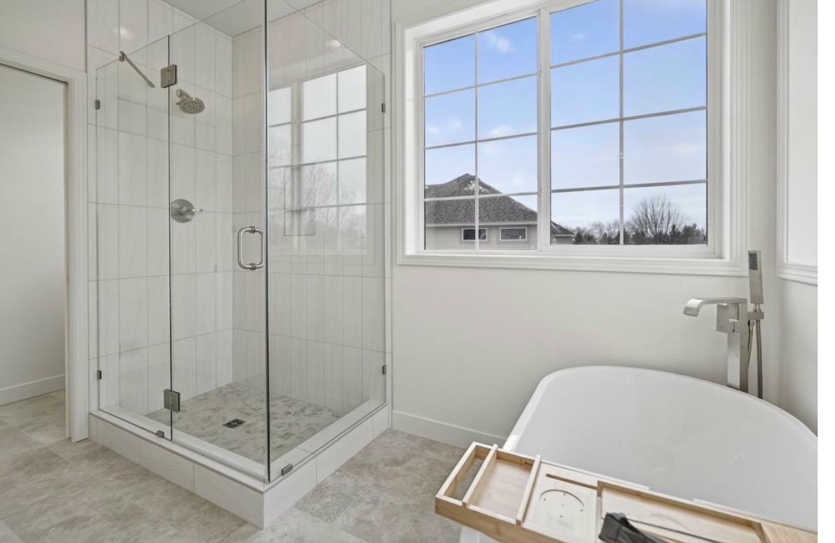 Primary bath after — frameless glass shower, soaker tub, natural light