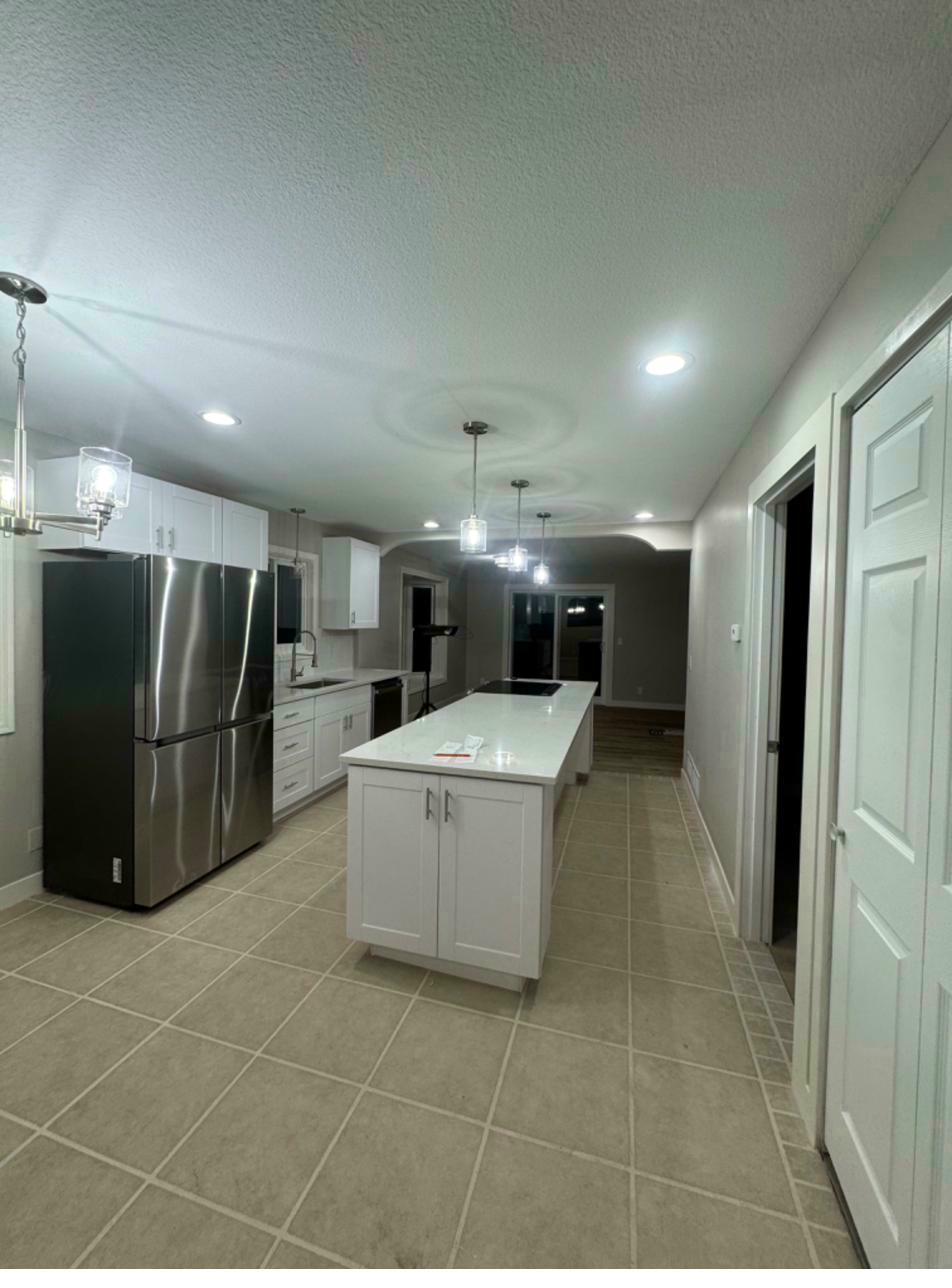 Kitchen after — white cabinetry, granite countertops, hardwood floors