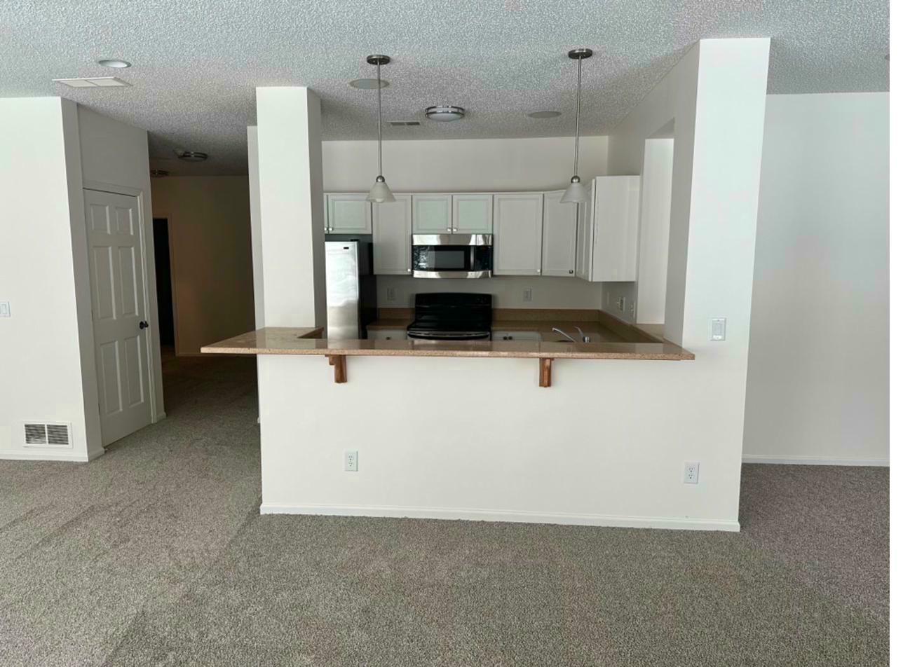 Basement kitchen after — white cabinetry, new flooring