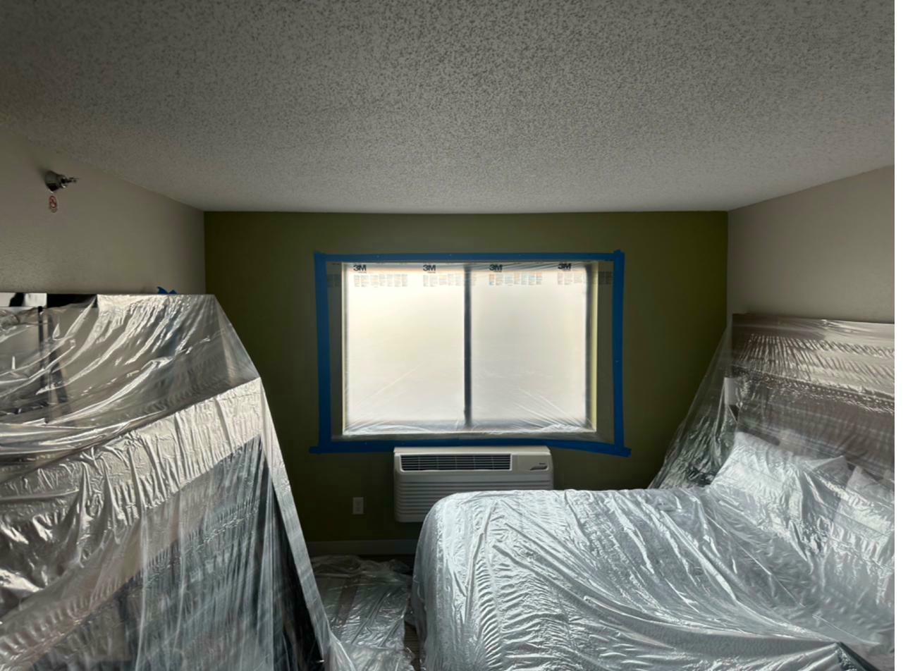 Hotel guest room mid-renovation — furniture wrapped, occupied building