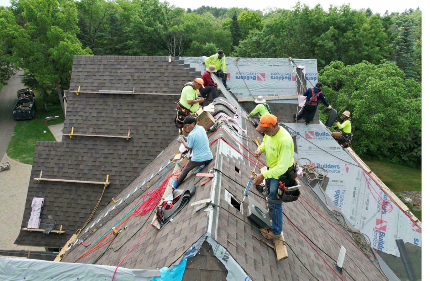 Roofing crew installing asphalt shingles — active job site