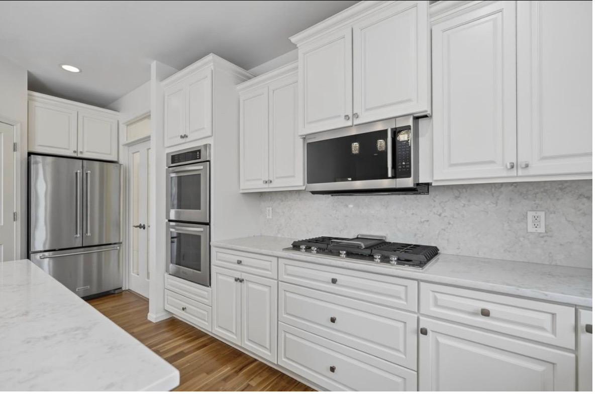 Kitchen after — white cabinetry, quartz countertops, double wall ovens