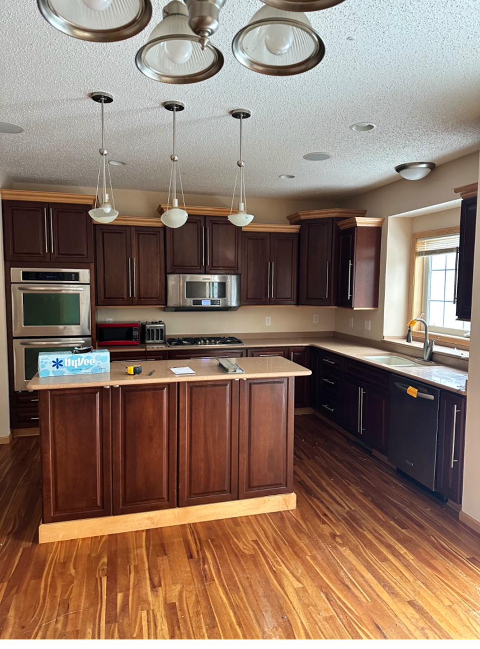 Kitchen before — dark cherry cabinetry, dated countertops